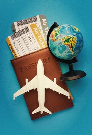 A small globe, toy airplane, passport, and airline tickets are arranged on a blue background, evoking a sense of adventure and travel planning. About Visa Services at Step By Step Consultant